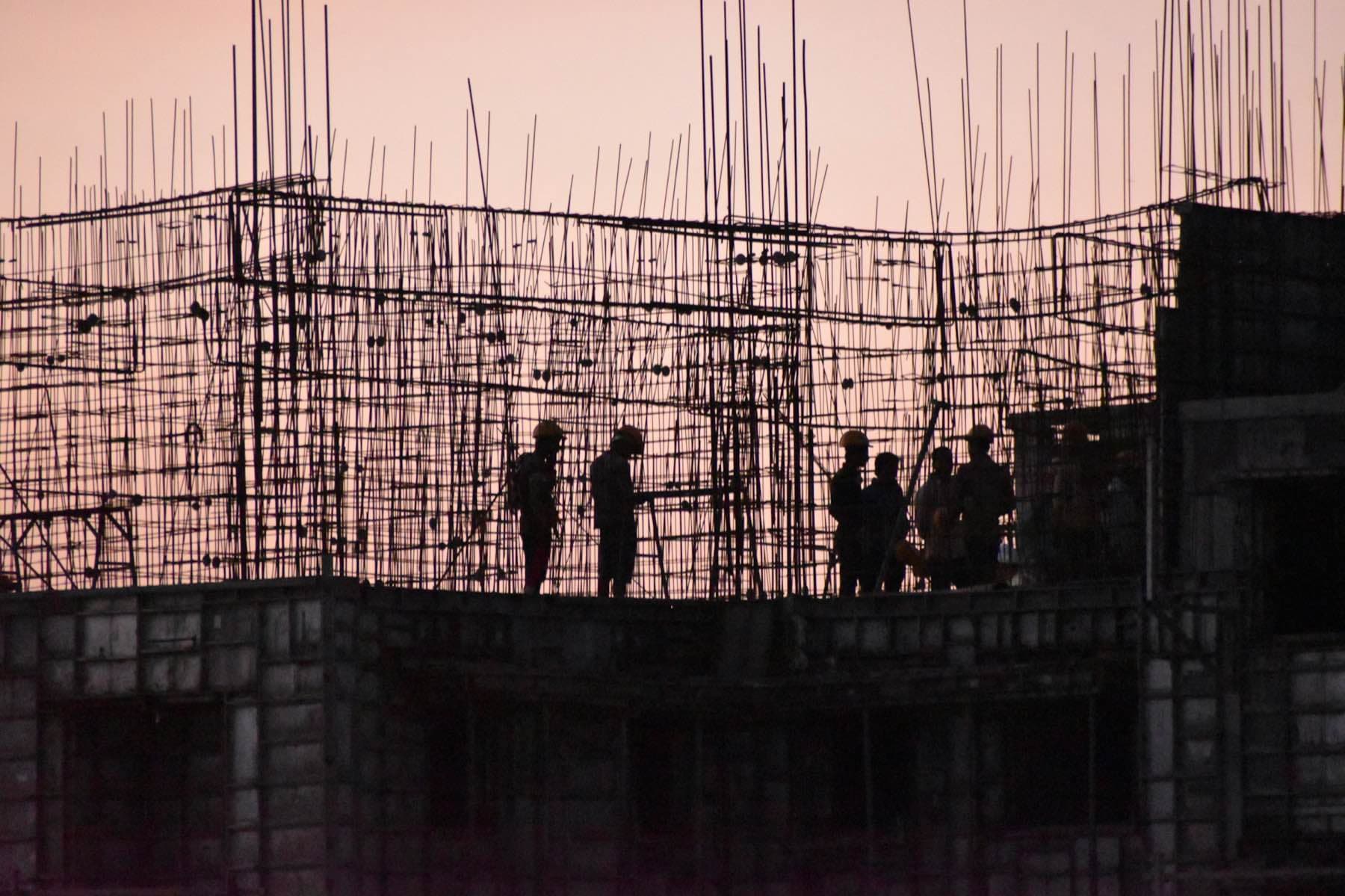 Construction workers silhouetted on a rebar frame at sunset